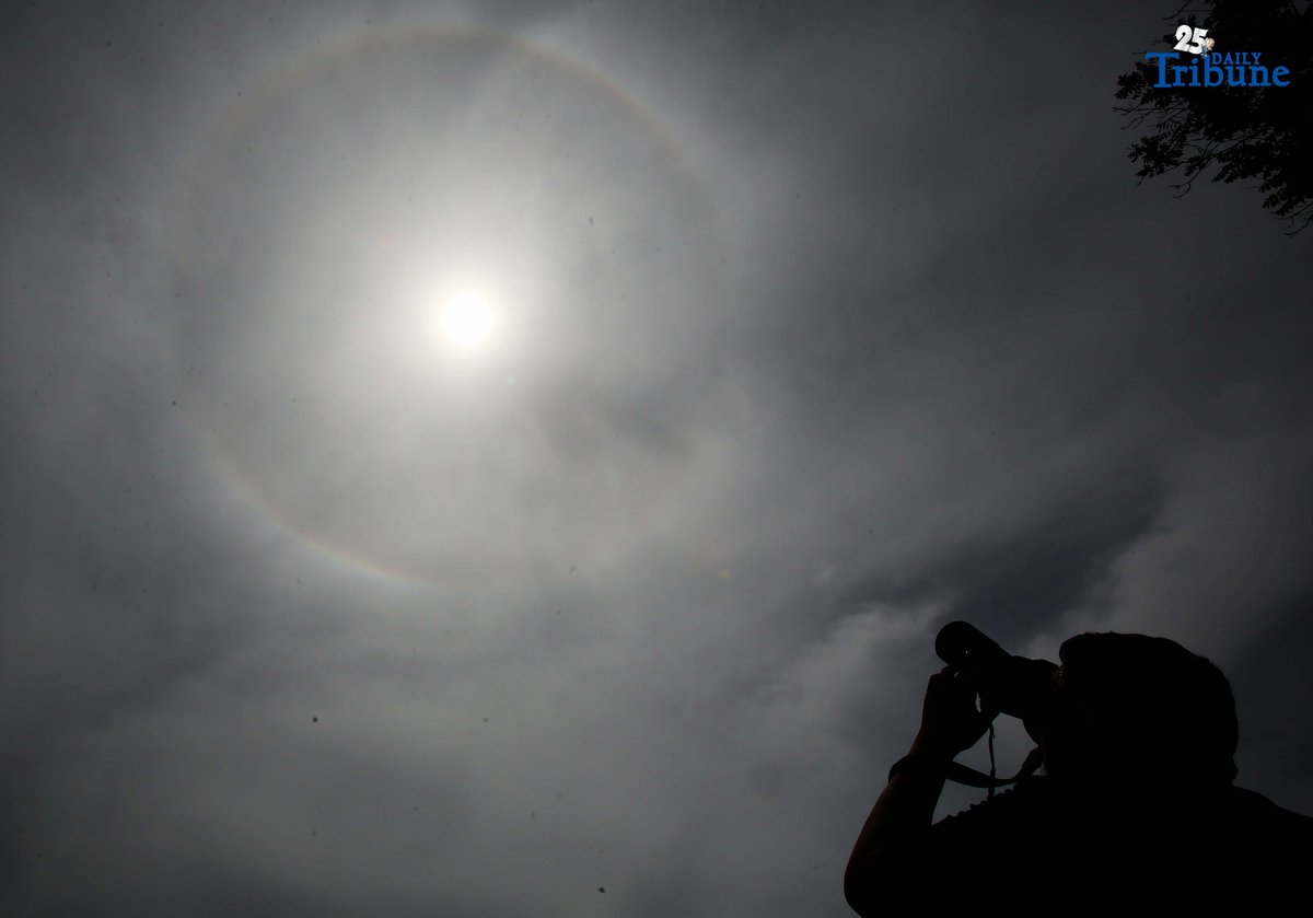 A photographer captures a visible sun halo in Quezon City on Monday. The atmospheric phenomenon occurs when sunlight refracts and reflects off tiny ice crystals suspended in high-altitude cirrus clouds.