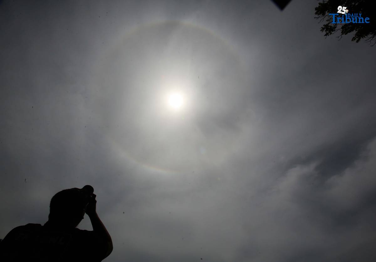 A photographer captures a visible sun halo in Quezon City on Monday. The atmospheric phenomenon occurs when sunlight refracts and reflects off tiny ice crystals suspended in high-altitude cirrus clouds.