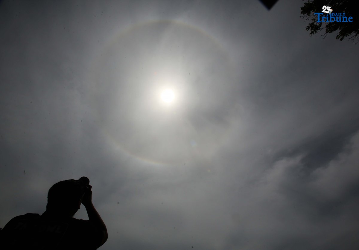 A photographer captures a visible sun halo in Quezon City on Monday. The atmospheric phenomenon occurs when sunlight refracts and reflects off tiny ice crystals suspended in high-altitude cirrus clouds.