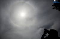 A photographer captures a visible sun halo in Quezon City on Monday. The atmospheric phenomenon occurs when sunlight refracts and reflects off tiny ice crystals suspended in high-altitude cirrus clouds.