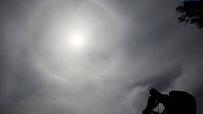A photographer captures a visible sun halo in Quezon City on Monday. The atmospheric phenomenon occurs when sunlight refracts and reflects off tiny ice crystals suspended in high-altitude cirrus clouds.