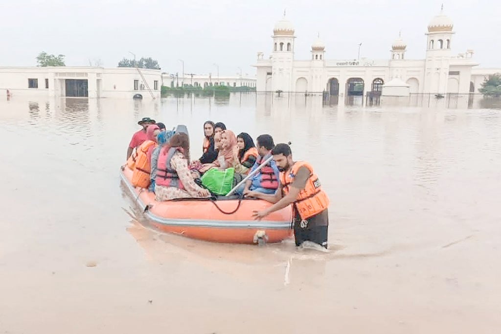 RESCUERS in a small boat transport people in the flooded area of the Kartarpur Sahib Corridor complex, which runs along the India-Pakistan border in Kartarpur.