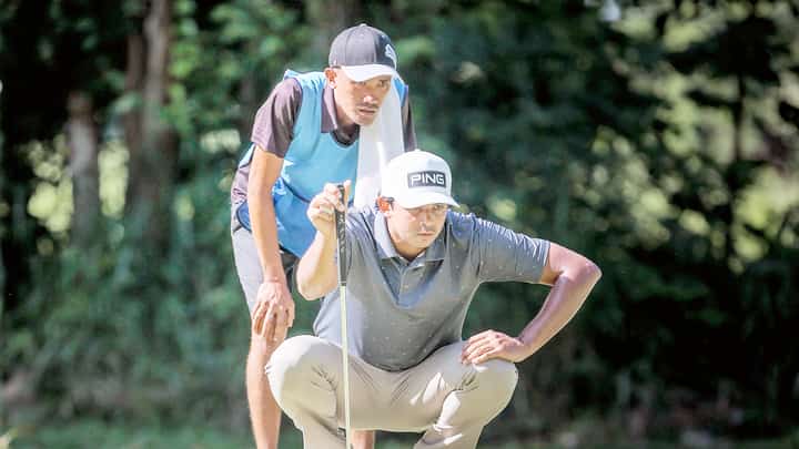 KEANU Jahns reads the line of his putt on his way to sharing the lead in the ICTSI Bacolod Challenge at the Bacolod Golf and Country Club on Wednesday.