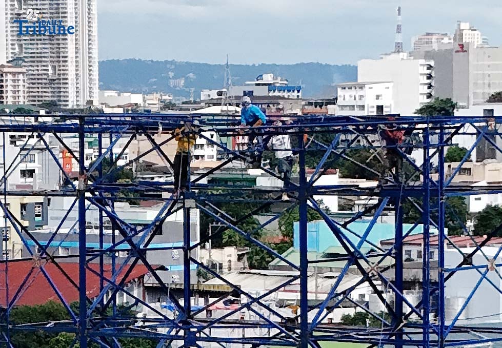 Workers were seen atop a construction billboard along EDSA in Quezon City on Thursday. On the same day, a Senate lawmaker presided over the first organizational meeting and public hearing of the Committee on Labor, Employment and Human Resource Development, which tackled proposed measures on minimum wage increases.