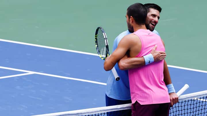 Spain's Carlos Alcaraz (R) and Serbia's Novak Djokovic (L) hug at the net after Alcaraz victory in their men's singles semifinal tennis match on day thirteen of the US Open tennis tournament at the USTA Billie Jean King National Tennis Center in New York City, on September 5, 2025.