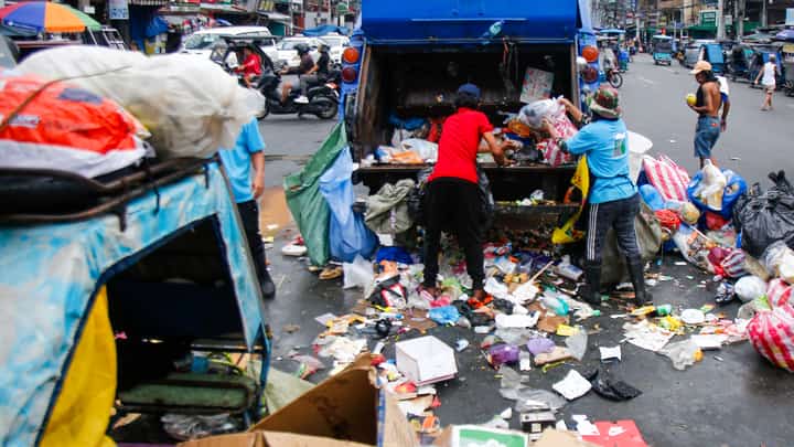 SANITATION workers collect garbage along Moriones Street in Tondo, Manila.