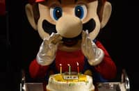 (FILES) This file photo taken on September 13, 2015 shows "Super Mario" attempting to blow out the candles on a cake during celebrations and a live performance of the most well-known Mario music to mark the game's 30th anniversary in Tokyo. Over four decades Nintendo's mascot "Super Mario" has run and jumped his way to global stardom, broadening the appeal of the video game industry as one of its top characters. September 13, 2025 will mark the 40th anniversary of the release of the 'Super Mario Bros' video game by Japanese video game maker Nintendo.