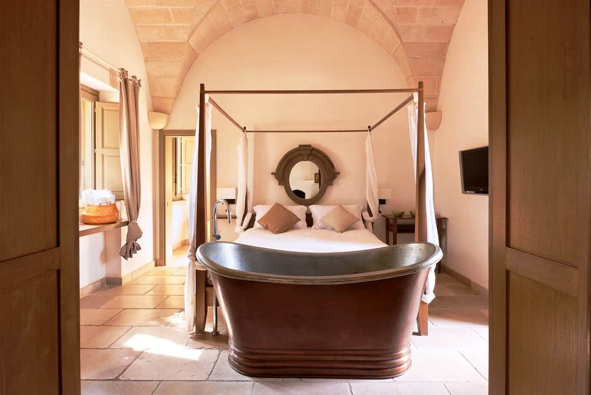 Under the elegant stone vaults in the bedroom is a four-poster bed covered with gauzy white drapes.