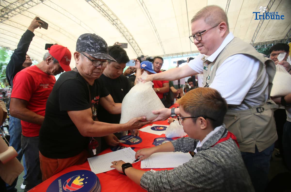 Agriculture Secretary Francisco Tiu Laurel Jr. assists in handing over P20-per-kilo rice to a tricycle driver during the rollout of the “Benteng Bigas, Meron Na!” project for the transport sector at the Kadiwa ng Pangulo Center in BAI, Quezon City on Tuesday.