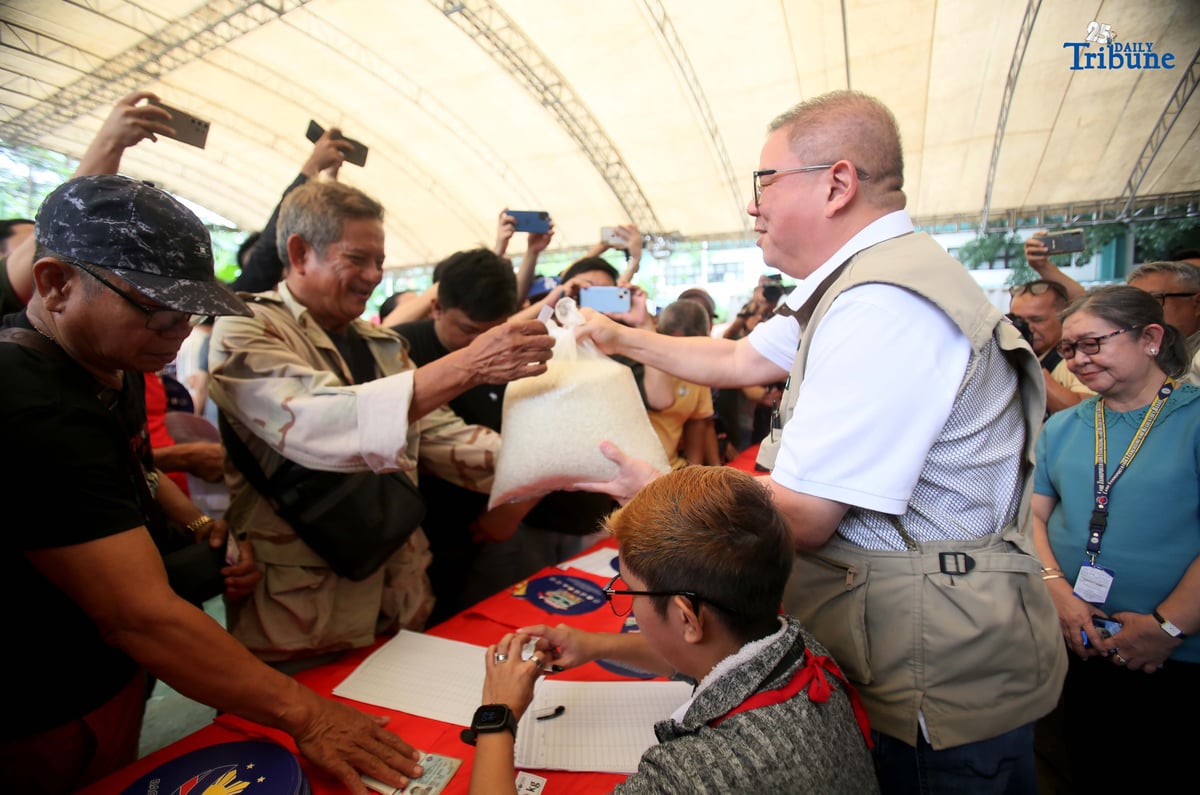 Agriculture Secretary Francisco Tiu Laurel Jr. assists in handing over P20-per-kilo rice to a tricycle driver during the rollout of the “Benteng Bigas, Meron Na!” project for the transport sector at the Kadiwa ng Pangulo Center in BAI, Quezon City on Tuesday.