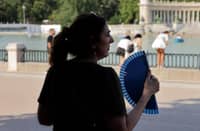 A woman uses a hand fan in a park during the first heatwave of the summer in Madrid, on June 28, 2025. Starting June 28, 2025 southern Europe will once again face extreme temperatures exceeding 40°C. Scientists warn that periods of extreme heat will become longer, more frequent and more intense as human-induced climate change accelerates.