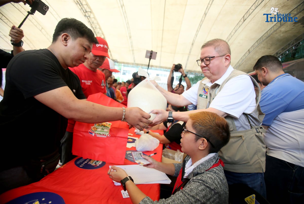 Agriculture Secretary Francisco Tiu Laurel Jr. assists in handing over P20-per-kilo rice to a tricycle driver during the rollout of the “Benteng Bigas, Meron Na!” project for the transport sector at the Kadiwa ng Pangulo Center in BAI, Quezon City on Tuesday.