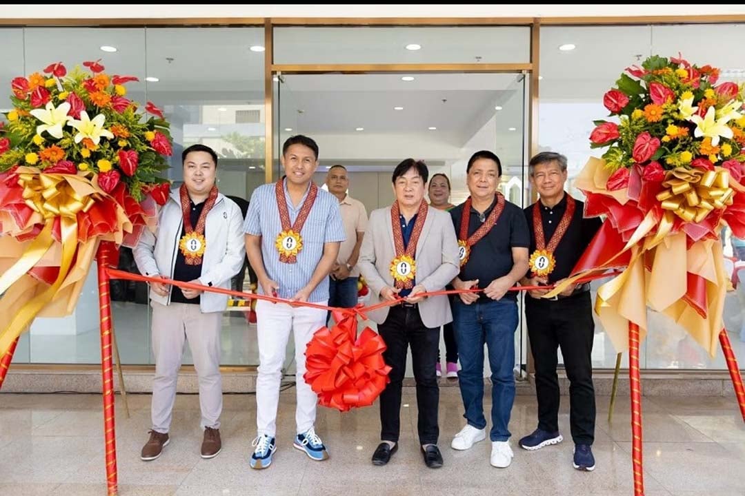 Executives and guests lead the ribbon-cutting ceremony to mark the opening of the new QSJ Motors dealership.
