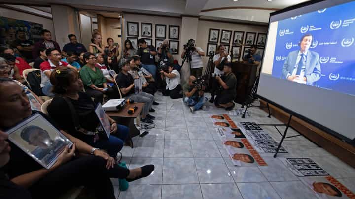 Silent witnesses Families of Duterte’s drug war victims clutch portraits as they watch the former president’s first ICC hearing streamed in a Manila church in March.
