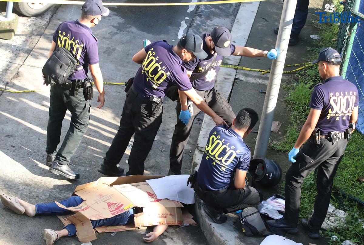 Scene of the Crime Operatives (QCPD-SOCO) examine the body of a man allegedly gunned down by motorcycle-riding assailants along Katipunan Avenue, Barangay Loyola Heights, Quezon City.