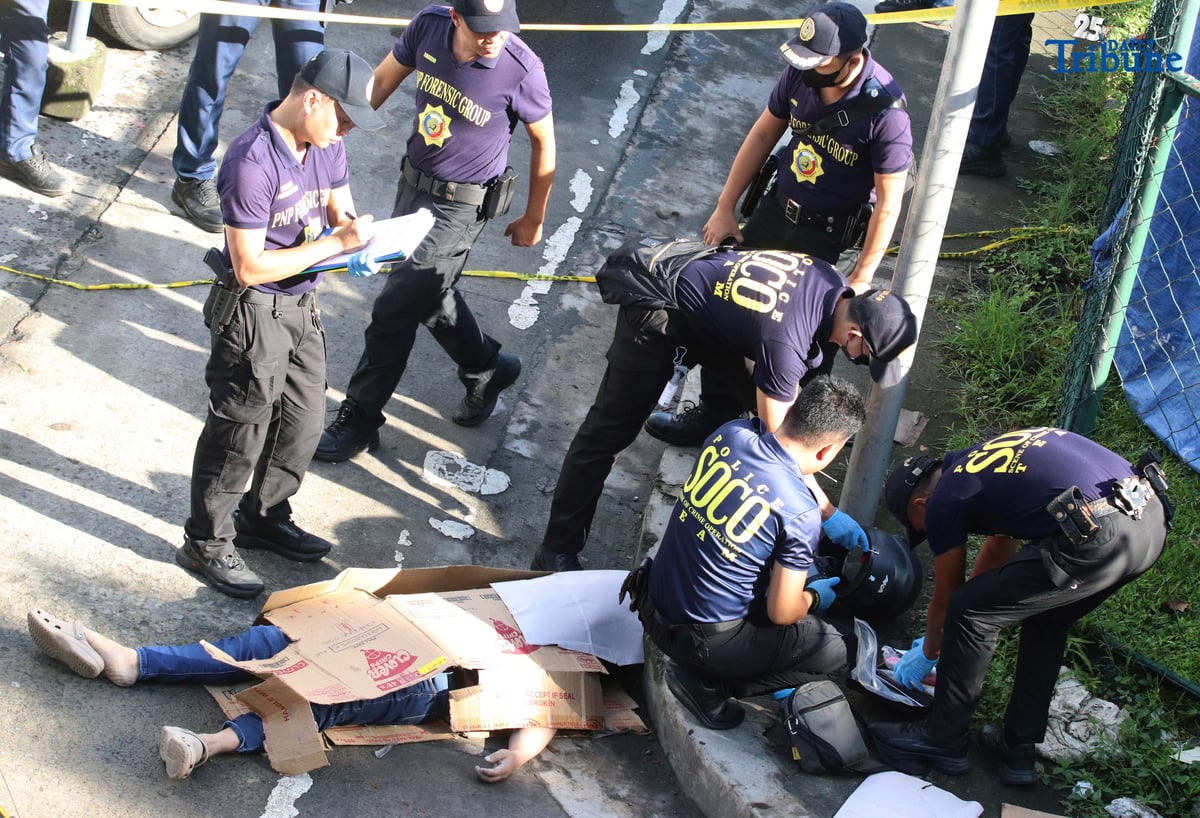 Scene of the Crime Operatives (QCPD-SOCO) examine the body of a man allegedly gunned down by motorcycle-riding assailants along Katipunan Avenue, Barangay Loyola Heights, Quezon City.