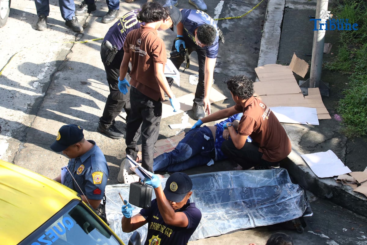 Scene of the Crime Operatives (QCPD-SOCO) examine the body of a man allegedly gunned down by motorcycle-riding assailants along Katipunan Avenue, Barangay Loyola Heights, Quezon City.