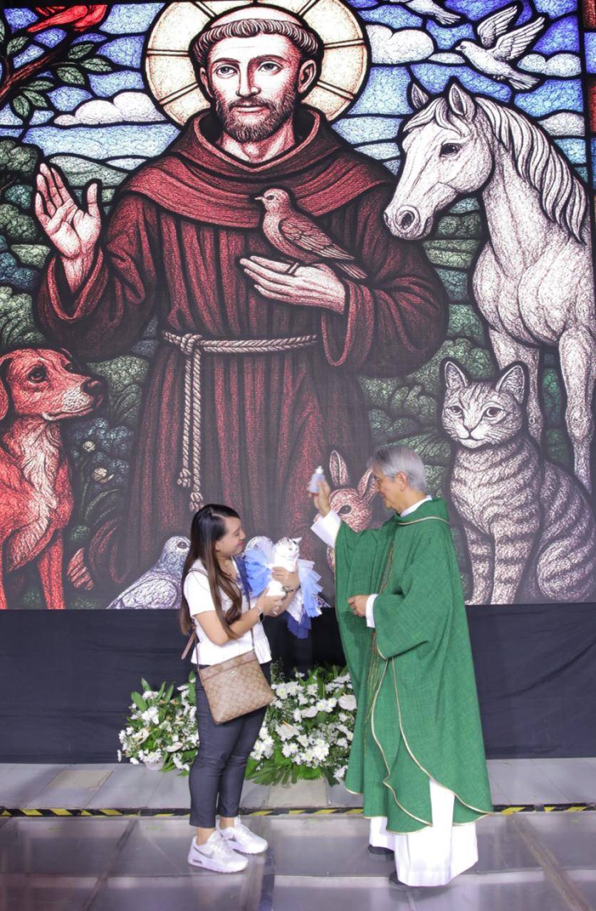 Fur mom and her feline companion being blessed by a priest.