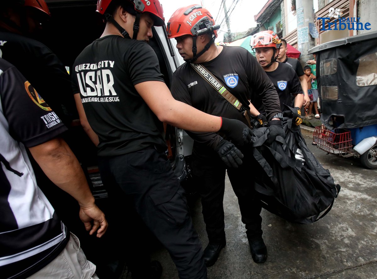 QCDRRMO-USAR personnel carry the body bags of three siblings who died in a third-alarm fire that struck a residential area along P. Florentino Street in Barangay Sto. Domingo, Quezon City, on Tuesday. The victims, aged 10, 7, and 5, were trapped inside their home as firefighters battled the blaze. Authorities are still investigating the cause of the fire.