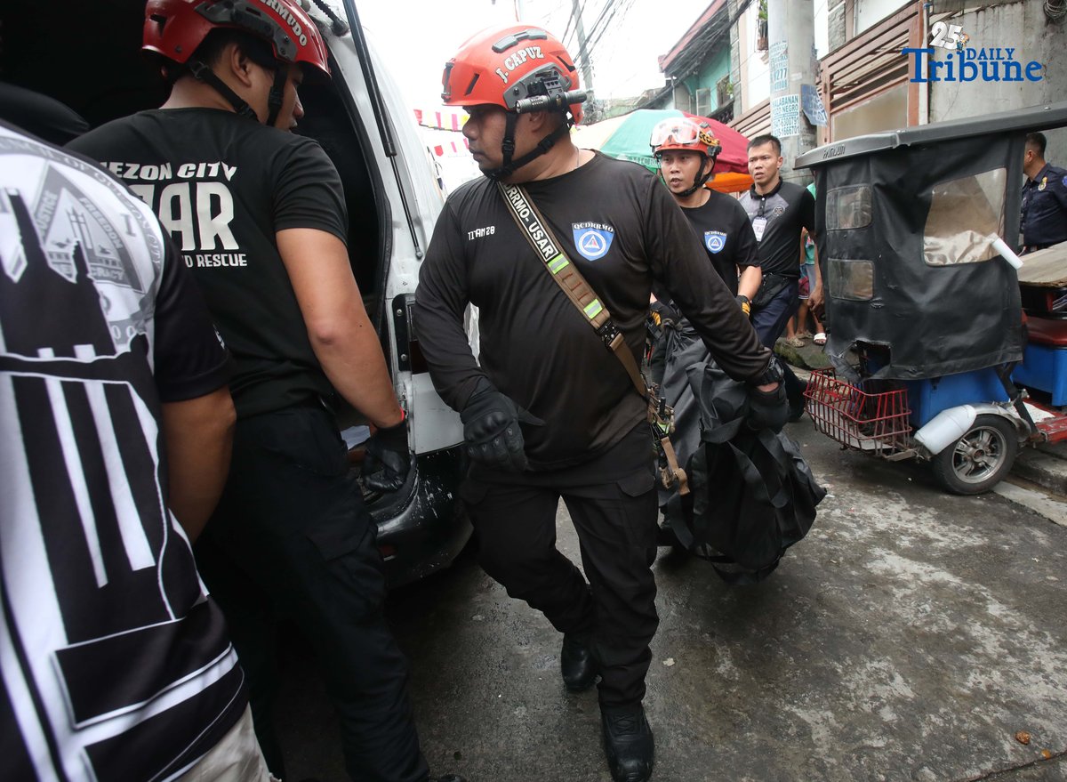 QCDRRMO-USAR personnel carry the body bags of three siblings who died in a third-alarm fire that struck a residential area along P. Florentino Street in Barangay Sto. Domingo, Quezon City, on Tuesday. The victims, aged 10, 7, and 5, were trapped inside their home as firefighters battled the blaze. Authorities are still investigating the cause of the fire.