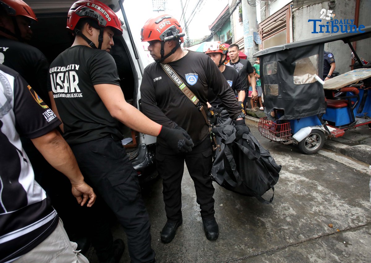 QCDRRMO-USAR personnel carry the body bags of three siblings who died in a third-alarm fire that struck a residential area along P. Florentino Street in Barangay Sto. Domingo, Quezon City, on Tuesday. The victims, aged 10, 7, and 5, were trapped inside their home as firefighters battled the blaze. Authorities are still investigating the cause of the fire.