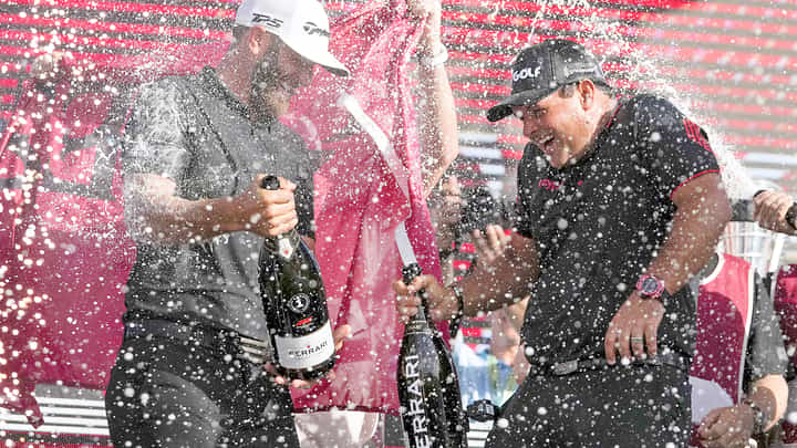 Team captain Dustin Johnson of 4 Aces GC and Patrick Reed celebrate on the podium after the team championship stroke-play round of the LIV Golf Invitational — Miami at Trump National Doral Miami in 2022 in Doral, Florida.