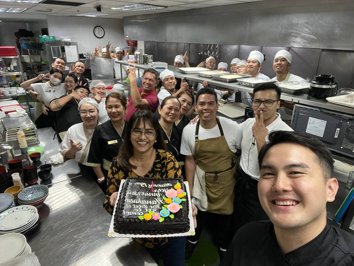 Yoshi (right, foreground) and mom Lorna holding the cake with the team.
