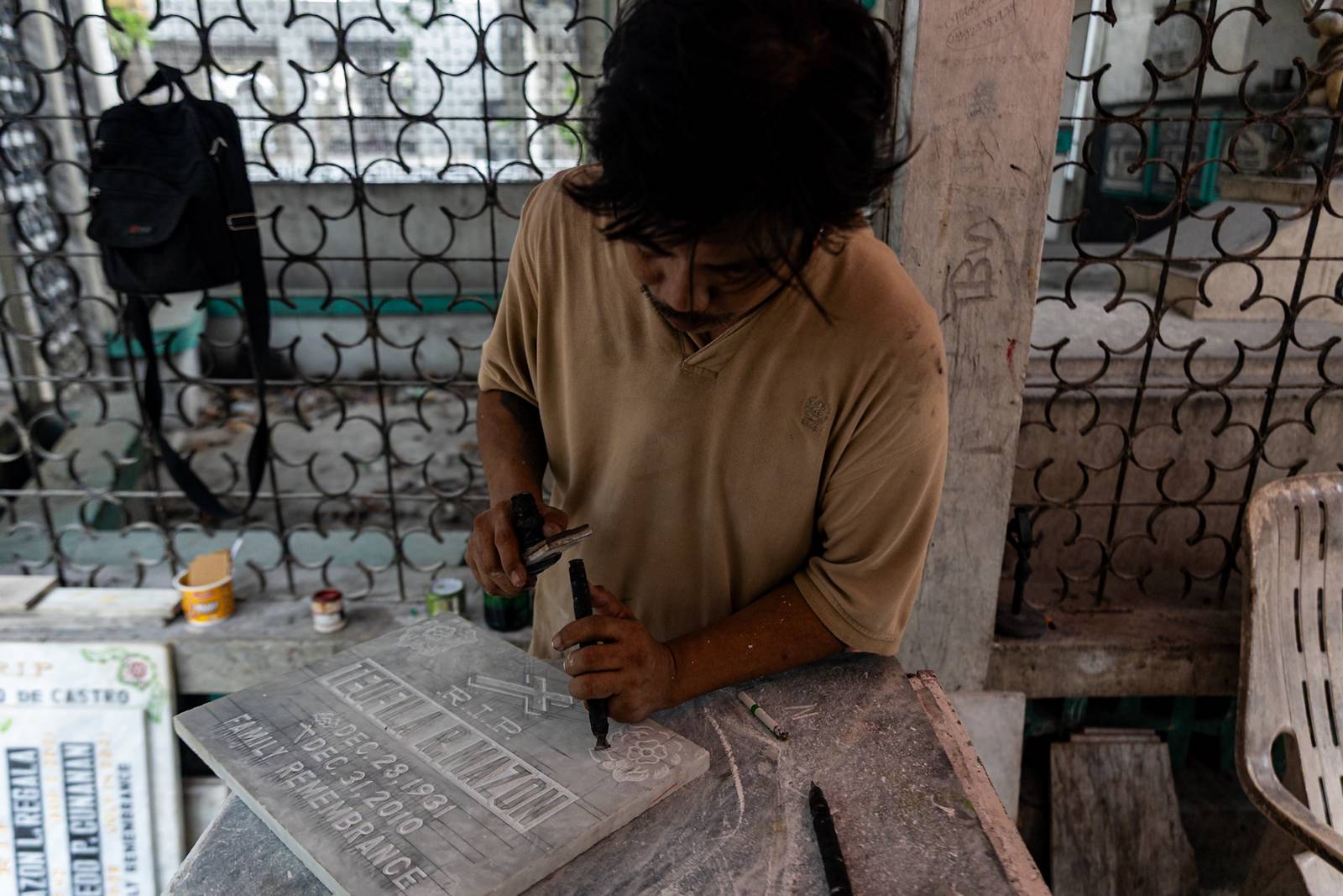 Tombstone maker Socsoc Gamurot engraves and paints names on a marble slab at his makeshift workshop inside the Manila North Cemetery as the annual observance of All Saints’ Day approaches.

 he 40-year-old, who resides inside the country’s largest cemetery, shares that each tombstone costs ₱1,200 and that he crafts an average of 10 pieces a day.