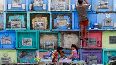 Informal settlers earn additional income during the observance of Undas by cleaning and repainting tombs and grave markers at the Manila North Cemetery.