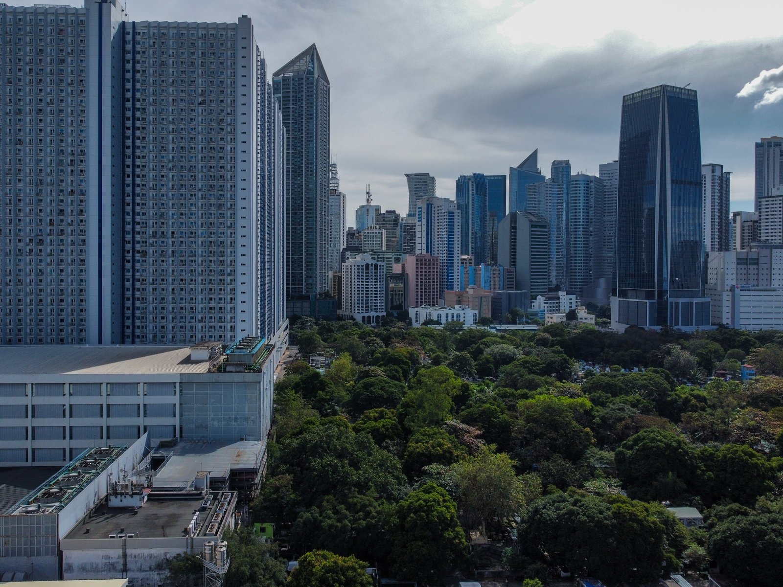 The vast greenery of Manila South Cemetery stands in contrast with the modern tall buildings of Makati City in this photo taken on All Saints' Day. As of 1:00 in the afternoon, at least 46,000 people have visited the Manila South Cemetery.