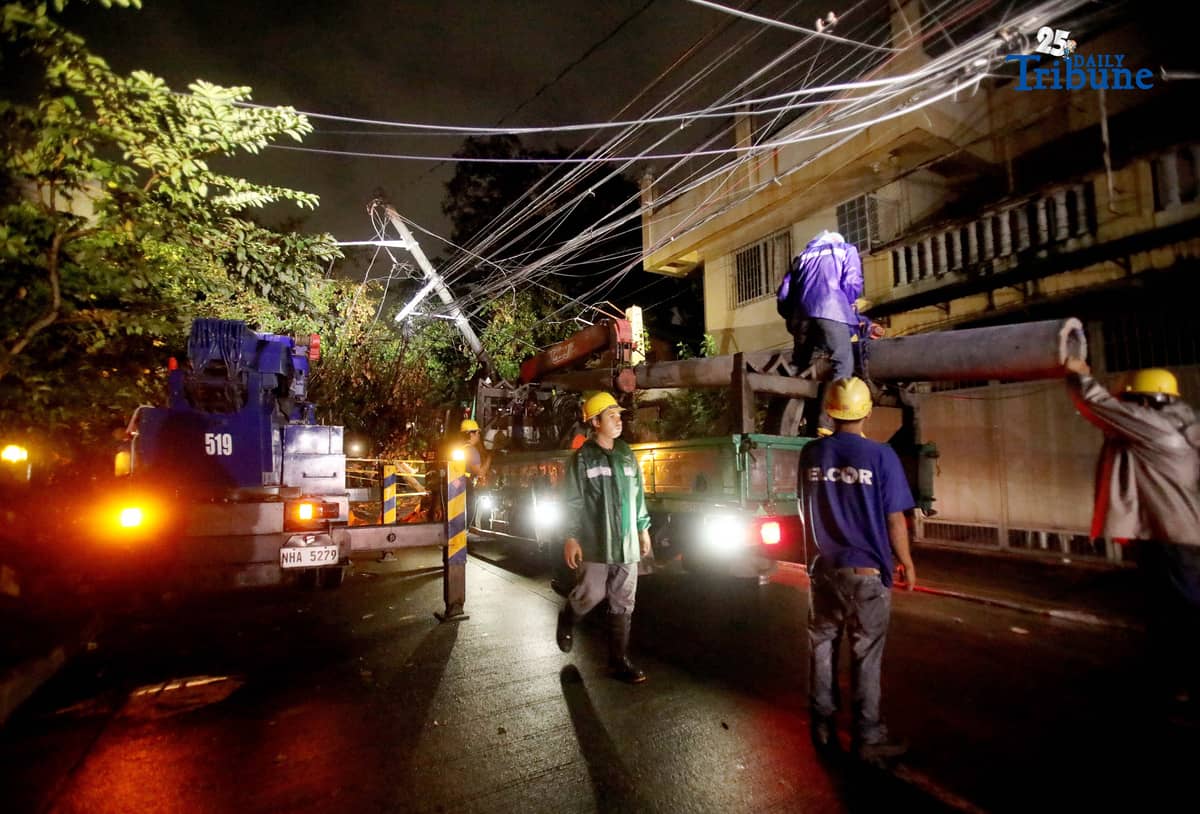ELCOR, a Meralco contractor, responds to a toppled electric post along K-1st Street in Quezon City early Monday, after strong winds from Super Typhoon Uwan caused a tree to fall and damage the line.