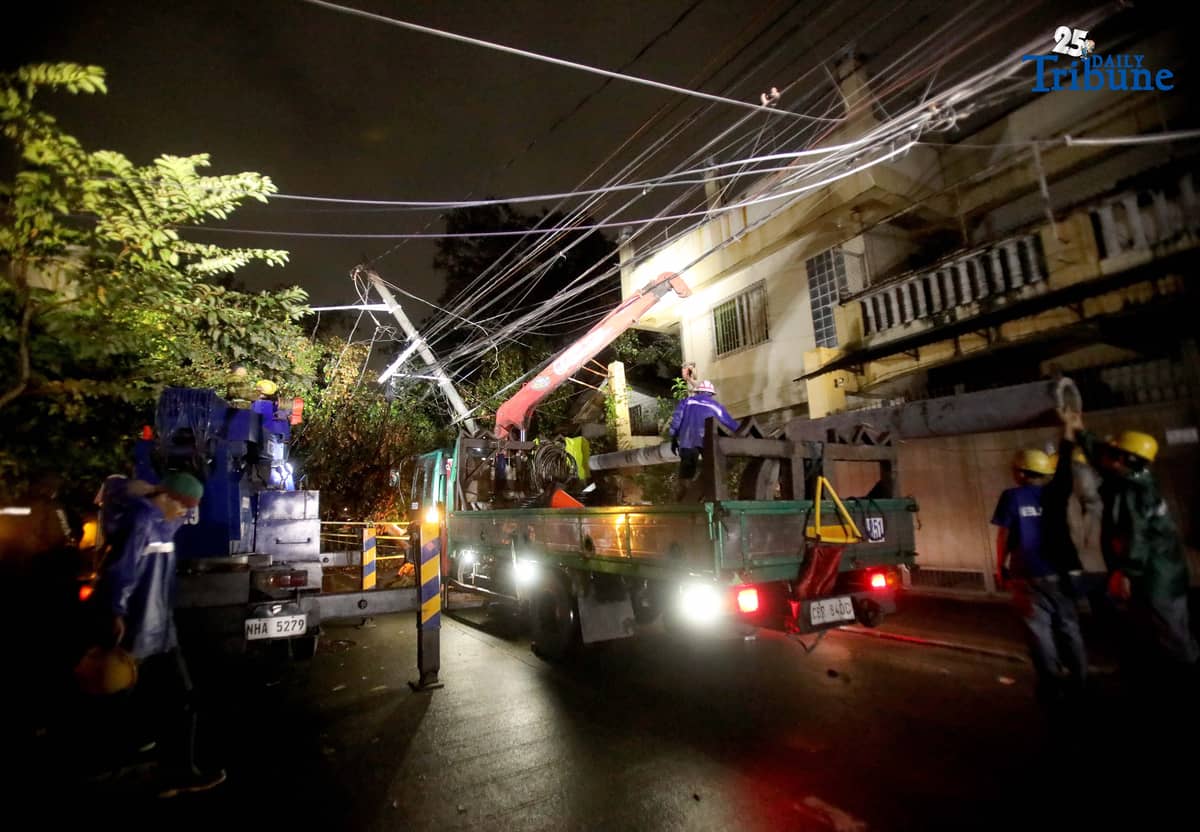 ELCOR, a Meralco contractor, responds to a toppled electric post along K-1st Street in Quezon City early Monday, after strong winds from Super Typhoon Uwan caused a tree to fall and damage the line.