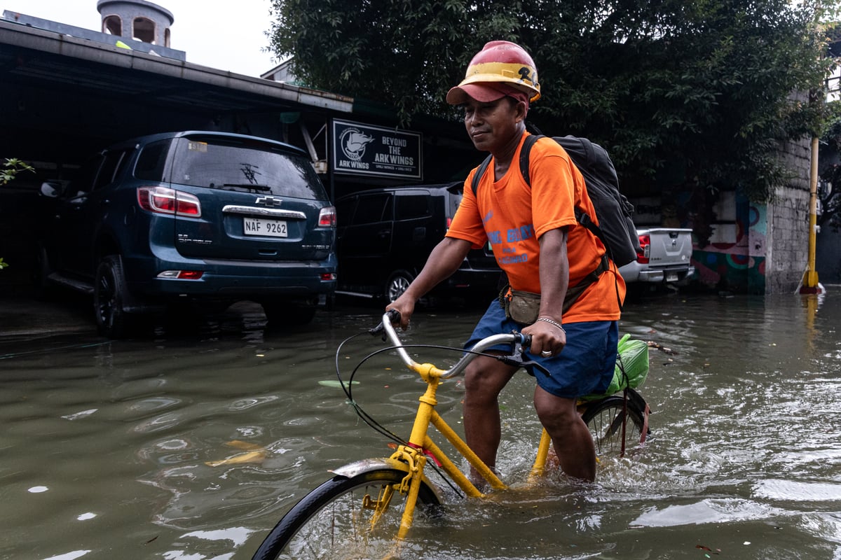 People wade through chest-deep floodwater in Barangay Navotas East, Navotas City on Monday, 10 November 2025, after the Malabon-Navotas Navigational Gate overflowed Sunday night amid high tide and storm surges driven by Super Typhoon Uwan.