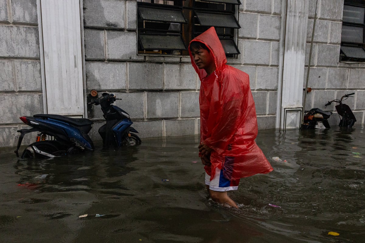 People wade through chest-deep floodwater in Barangay Navotas East, Navotas City on Monday, 10 November 2025, after the Malabon-Navotas Navigational Gate overflowed Sunday night amid high tide and storm surges driven by Super Typhoon Uwan.