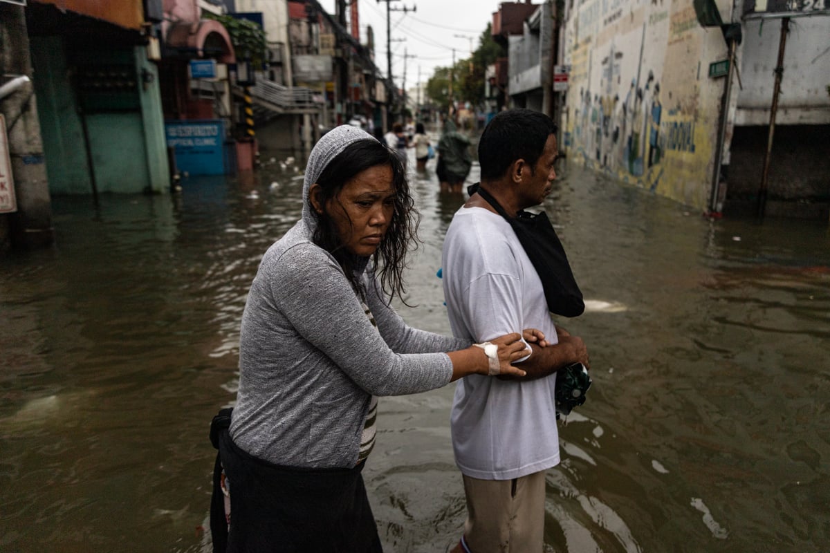 People wade through chest-deep floodwater in Barangay Navotas East, Navotas City on Monday, 10 November 2025, after the Malabon-Navotas Navigational Gate overflowed Sunday night amid high tide and storm surges driven by Super Typhoon Uwan.