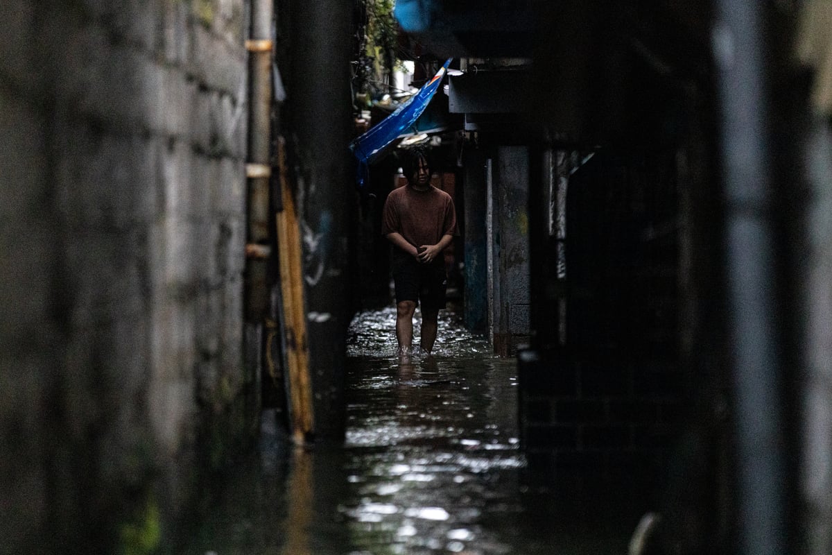 People wade through chest-deep floodwater in Barangay Navotas East, Navotas City on Monday, 10 November 2025, after the Malabon-Navotas Navigational Gate overflowed Sunday night amid high tide and storm surges driven by Super Typhoon Uwan.