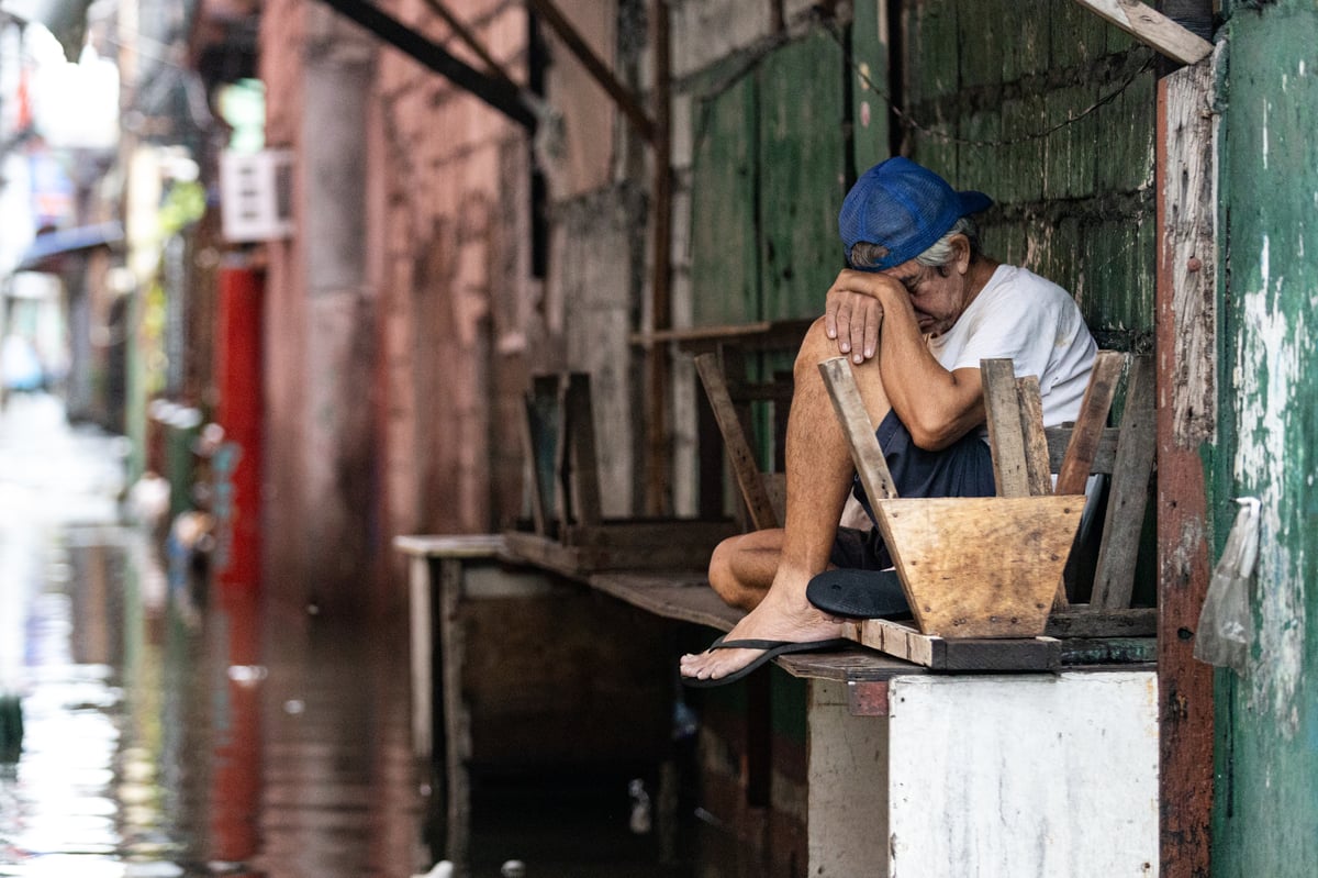 People wade through chest-deep floodwater in Barangay Navotas East, Navotas City on Monday, 10 November 2025, after the Malabon-Navotas Navigational Gate overflowed Sunday night amid high tide and storm surges driven by Super Typhoon Uwan.