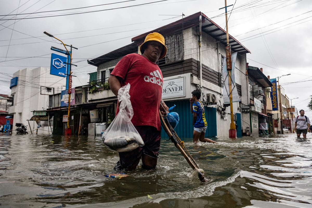 People wade through chest-deep floodwater in Barangay Navotas East, Navotas City on Monday, 10 November 2025, after the Malabon-Navotas Navigational Gate overflowed Sunday night amid high tide and storm surges driven by Super Typhoon Uwan.