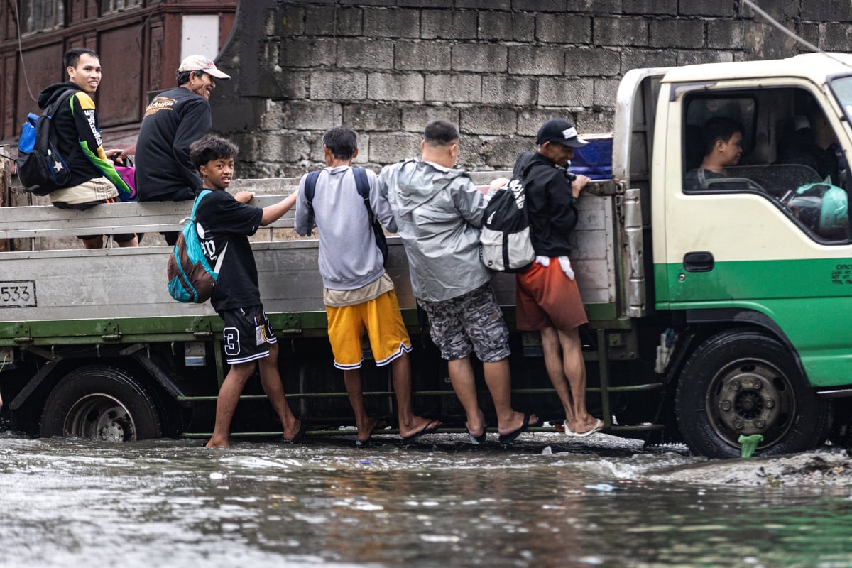 People wade through chest-deep floodwater in Barangay Navotas East, Navotas City on Monday, 10 November 2025, after the Malabon-Navotas Navigational Gate overflowed Sunday night amid high tide and storm surges driven by Super Typhoon Uwan.