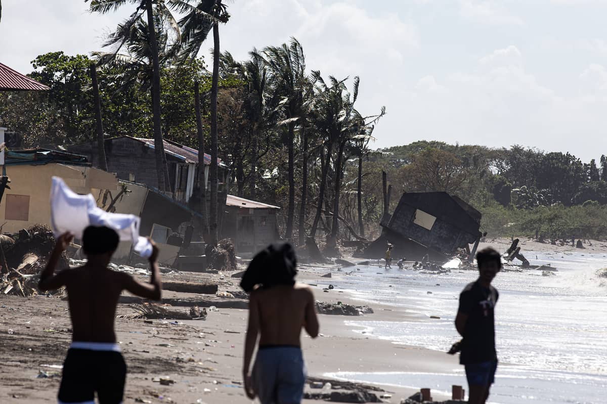 People walk along the shoreline near damaged houses caused by Super Typhoon Uwan in the coastal barangay Julugan 8 in Tanza, Cavite on Tuesday.