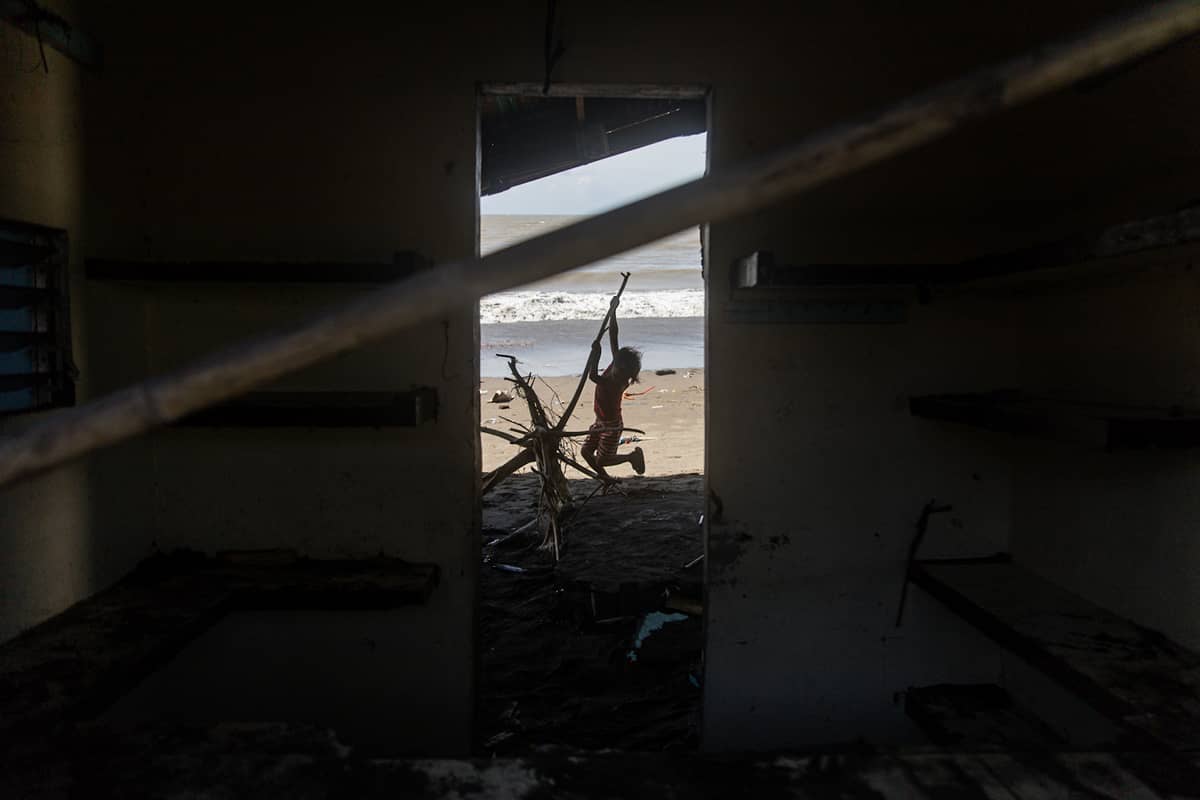 A child is seen playing outside a damaged house in the coastal barangay Julugan 8, Tanza, Cavite on Tuesday.
