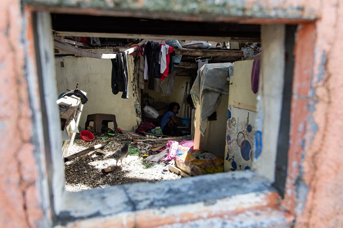 A woman does her laundry inside her destroyed home in the coastal barangay Amaya V, Tanza, Cavite on Tuesday.