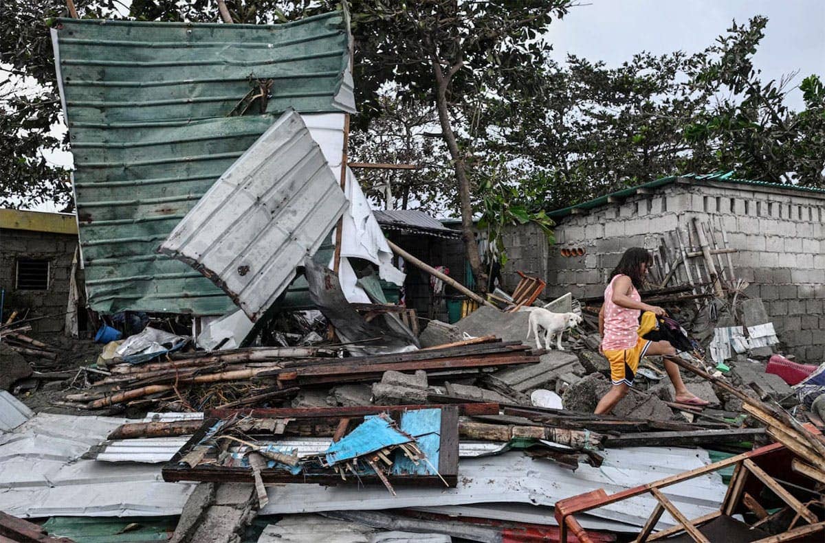 A woman walks on the damaged houses left by Super Typhoon Uwan.