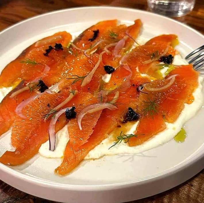 Gravlax Salmon layered with orange, ginger, onion, crispy chili and a touch of ricotta.