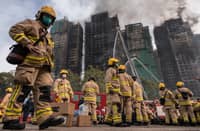 (FILE) Firemen get ready after a major fire swept through several apartment blocks at the Wang Fuk Court residential estate in Hong Kong's Tai Po district on November 27, 2025. Hong Kong firefighters were scouring a still-burning apartment complex for hundreds of missing people on November 27, a day after the blaze tore through the high-rises, killing at least 44.