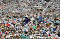 Two workers stand in a landfill.