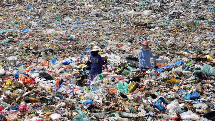 Two workers stand in a landfill.