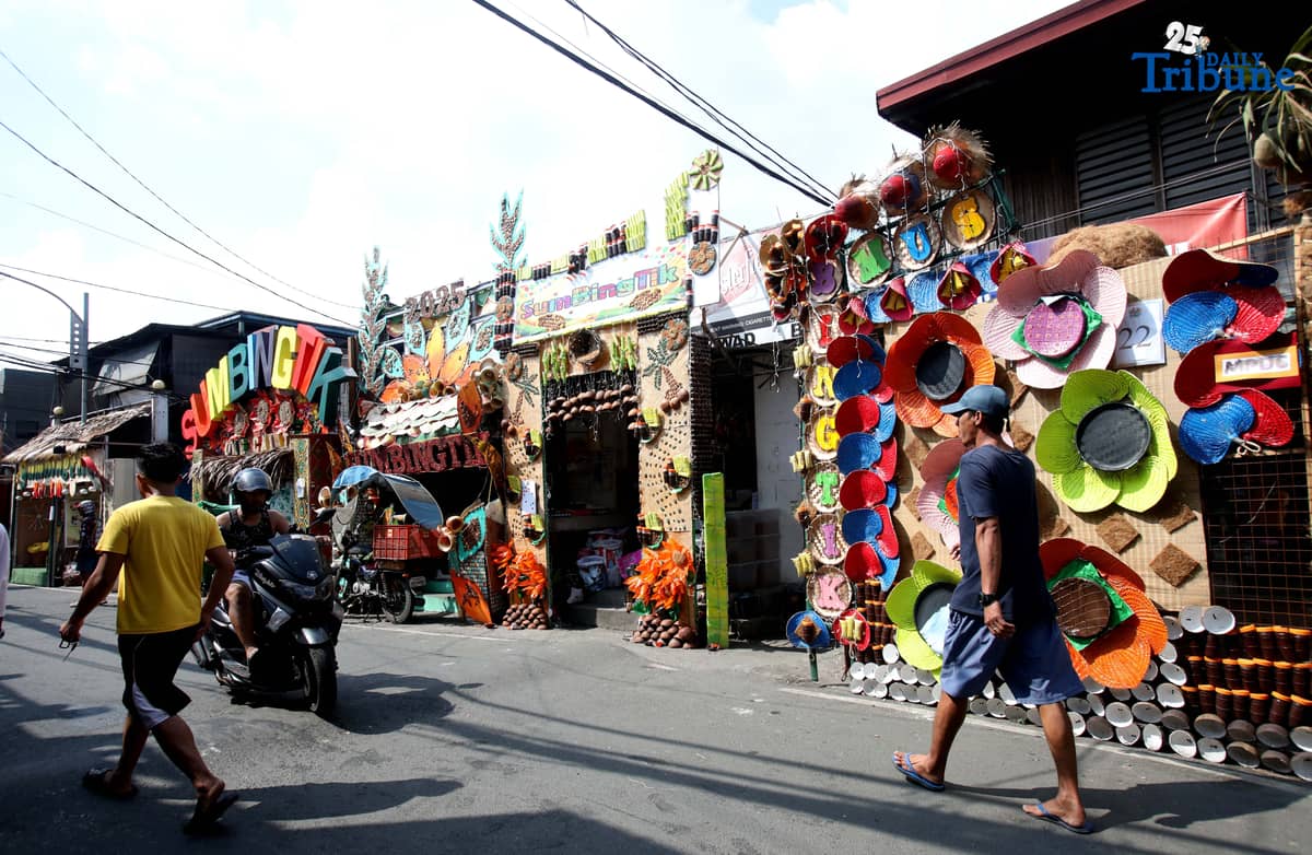 (December 01 2025) Pedestrians walk past houses decorated with colourful reusable materials as part of the 2025 SumBingTik (Suman, Bibingka, Latik) Festival in Cainta, Rizal on Monday December 1 2025. The SumBingTik Festival is an annual cultural long-week festival held in Cainta, Rizal, along with the town's founding anniversary and the feast of Our Lady of Light which is celebrated on December 1, the patron saint of the town. The festival was first celebrated in 2014. Photo/Analy Labor