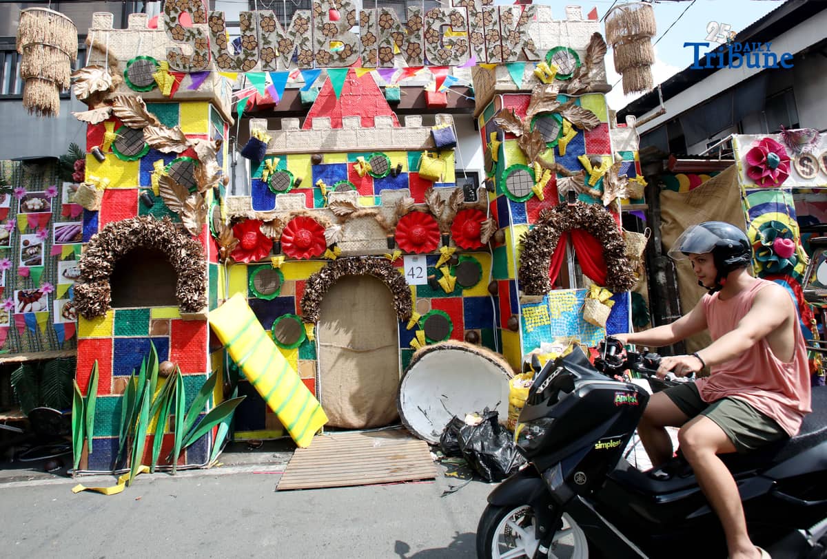 (December 01 2025) Pedestrians walk past houses decorated with colourful reusable materials as part of the 2025 SumBingTik (Suman, Bibingka, Latik) Festival in Cainta, Rizal on Monday December 1 2025. The SumBingTik Festival is an annual cultural long-week festival held in Cainta, Rizal, along with the town's founding anniversary and the feast of Our Lady of Light which is celebrated on December 1, the patron saint of the town. The festival was first celebrated in 2014. Photo/Analy Labor