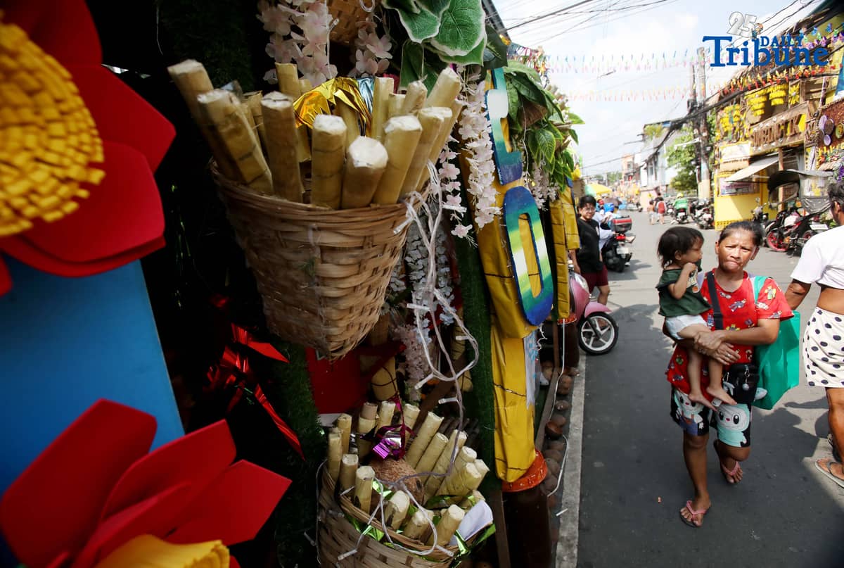 (December 01 2025) Pedestrians walk past houses decorated with colourful reusable materials as part of the 2025 SumBingTik (Suman, Bibingka, Latik) Festival in Cainta, Rizal on Monday December 1 2025. The SumBingTik Festival is an annual cultural long-week festival held in Cainta, Rizal, along with the town's founding anniversary and the feast of Our Lady of Light which is celebrated on December 1, the patron saint of the town. The festival was first celebrated in 2014. Photo/Analy Labor
